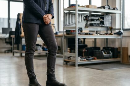 Femme portant des chaussures de sécurité élégantes style bottines noires dans un environnement de travail industriel moderne