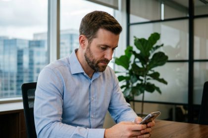 Jeune homme professionnel utilisant son smartphone dans un bureau moderne